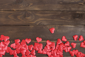 Lot bulk red hearts on a wooden table.