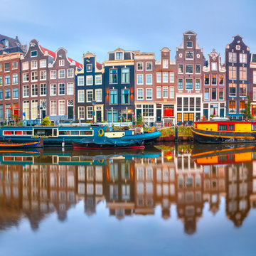 Amsterdam canal Singel with typical dutch houses and houseboats during morning blue hour, Holland, Netherlands.
