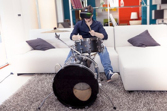 young adult playing drums at home using viewer for virtual reali