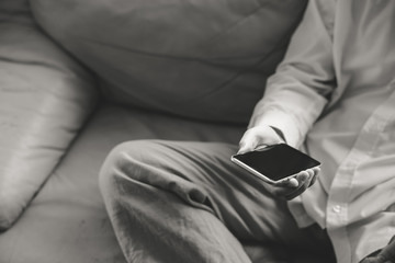 Closeup on mobile phone in hand of young man sitting