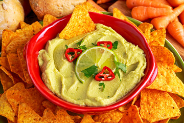 Classic Homemade avocado hummus with olive oil, carrots, pita chips, lime, chilli, parsley.