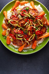takeawy classic pork on rice with fried in sticky souce carrots, sprinkle of chillie and spring onion.