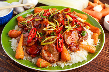 takeawy classic pork on rice with fried in sticky souce carrots, sprinkle of chillie and spring onion.