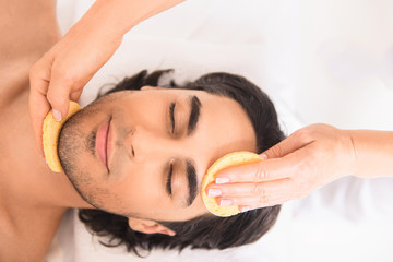 Calm guy enjoying face massage at beauty salon