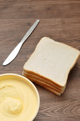 Butter, bread and a knife isolated on a wooden background