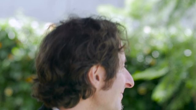 A handsome business man with half a beard performing a strange dance outside