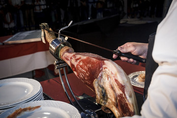 Cortador de jamón cortando un cinco jotas. degustación de jamón ibérico de bellota. Noches gastronómicas de verano.