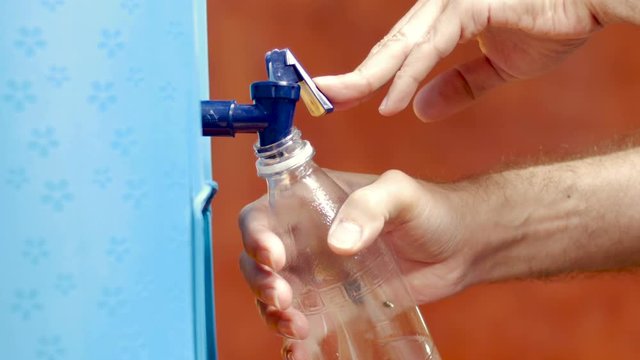 A Man Refills A Plastic Water Bottle From A Water Cooler