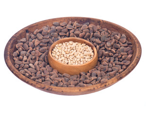 Organic pine nuts with and without shell in wooden bowls separated on white background