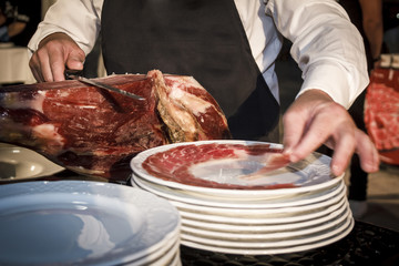 Cortador de jamón cortando un cinco jotas. degustación de jamón ibérico de bellota. Noches gastronómicas de verano.