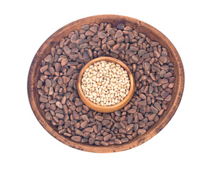 Organic pine nuts with and without shell in wooden bowls separated on white background