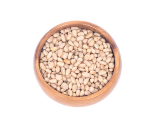 Organic pine nuts in wooden bowl separated on white background