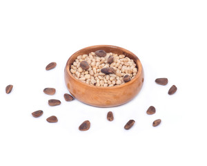 Organic pine nuts with and without shell in wooden bowl on white background