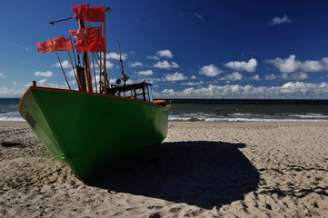 Zielony kuter rybacki stojący na piaszczystej plaży. - obrazy, fototapety, plakaty