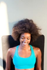 Fototapeta na wymiar Young happy woman sitting on the mat having a rest after fitness