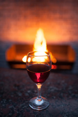 glass of red wine with fire on background;