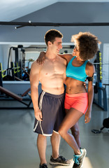Fototapeta na wymiar Athletic man and afro american woman posing in gym. Couple that trains together stays together