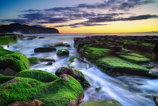 The wave flows over weathered rocks and boulders at Turimetta Be