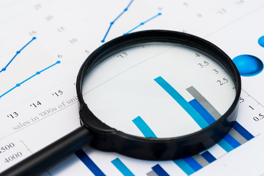 Business Analysis Image - magnifying glass on graphs and spreadsheet