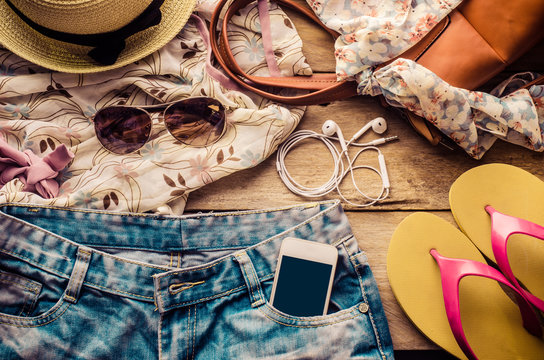 accessories for teenage girl on her vacation, hat, stylish for summer sunglasses, leather bag, sneakers and costume on wooden floor.