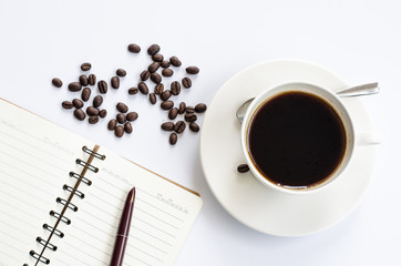 Coffee beans and cup of coffee on white with notebook and pen