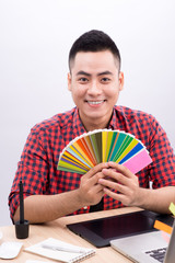 Happy asian male graphic designer holding color fan in his hand