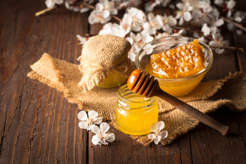 Honey dripping from a wooden honey dipper in a jar on wooden grey rustic background. Propolis and...