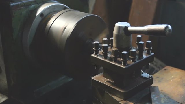 Finishing metal working on lathe grinder machine in workshop.