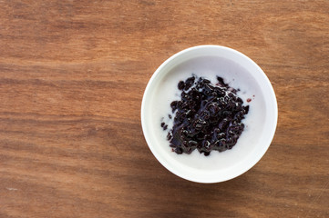 Black sticky rice pudding with coconut milk in glass bowl, Thai dessert