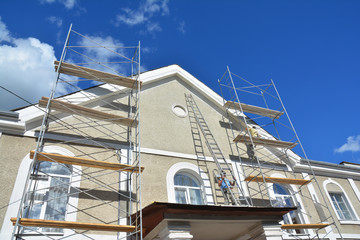 Painting and Plastering Exterior House Scaffolding Wall. Home Facade Insulation, Stucco and...