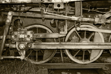 Fototapeta na wymiar Black and white. Old, vintage locomotive which stands on the rails. Rusty and dirty train wheels close up. The train made in the distant past.