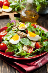 Fresh salad with chicken, tomatoes, eggs and arugula on plate