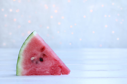 sweet tasty holiday/ slice of ripe watermelon on a wooden surface and the background of lights 