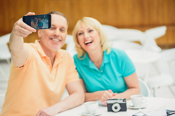 Happy married couple photographing themselves on phone