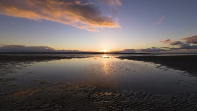 Timelapse of sandy beach at sunset with tide out