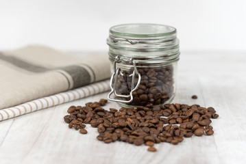 Coffee beans in a glass jar on wooden background. 