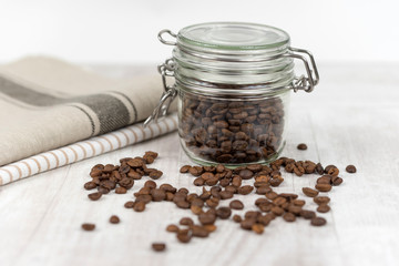 Coffee beans in a glass jar on wooden background. 