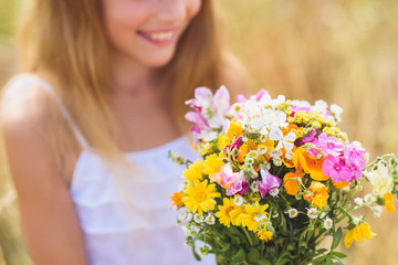 Obraz na płótnie Canvas Joyful female kid adores field bouquet