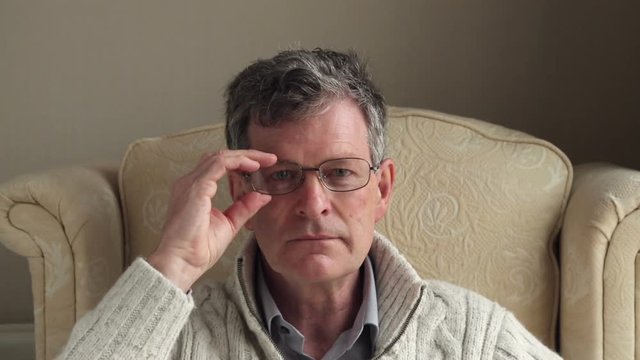 Senior man turns to camera and puts on glasses
