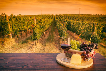 Glass of red wine in front of a vineyard at sunset