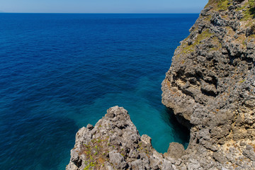 View from a rocky cliff into a turquoise tropical sea.