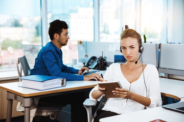 Young beautiful female support phone operator speaking, consulting, over office background.