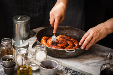Person preparing fresh sausage with smoked paprika for baker in oven. 