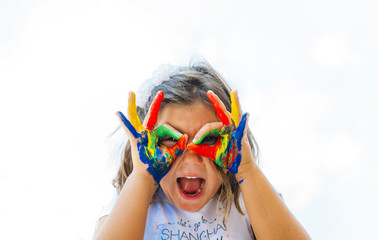 Happy cute girl with hands and face painted colors