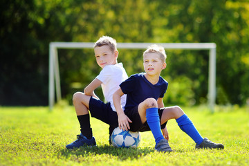 Two little brothers having fun playing a soccer game on sunny summer day