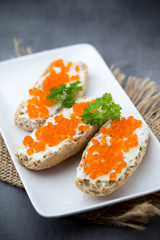 Red caviar on bread on white plate.