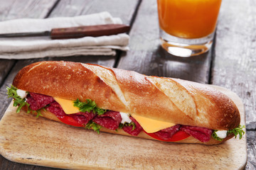 baguette sandwich with salami and herbs on a wooden surface