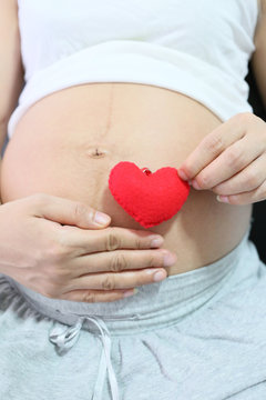 Red heart symbol in hand a asian women pregnant.