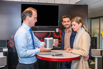 Assistant Showing Compact Speaker To Couple In Shop