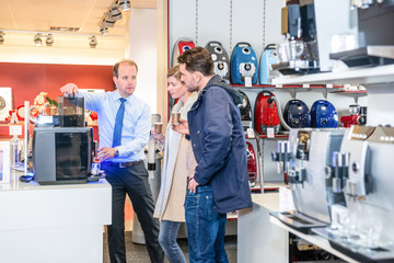 Salesman Showing Coffee Maker To Couple In Store - obrazy, fototapety, plakaty
